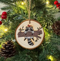 a wooden ornament with a raccoon on it hanging from a christmas tree