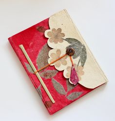 a red book with an umbrella and flower design on the cover is next to a pair of chopsticks