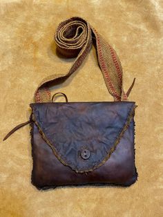 Handsewn and  lined goat hide pouch  (161)  measuring 7″ x 8.5″.  Flap is secured with leather button.  Seams are fully welted. Has interior pocket. Antiqued jute 2″ wide strap. Rustic Bags With Leather Lining For Everyday Use, Rustic Leather-lined Bag For Everyday Use, Rustic Everyday Bags With Leather Lining, Rustic Brown Bags With Leather Lining, Rustic Brown Leather Bag, Rustic Leather Bags With Waxed Finish, Rustic Leather Shoulder Bag For Everyday Use, Rustic Leather Shoulder Bag With Leather Handles, Rustic Brown Bag With Waxed Finish