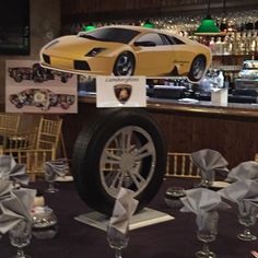 a car on display at a bar with silver napkins and wine glasses around it