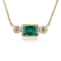 A modern and sleek, three-stone emerald & diamond bezel necklace. This gorgeous necklace has a vibrant and lustrous, earth-mined, natural emerald bezel set East to West. Large, brilliant round diamonds set alongside creating a timeless yet modern styled necklace. The chain is stationary, 18 inches long.   Setting Style: Bezel Setting Material: 14K Yellow Gold Setting Weight: 5.3 Grams Main Stone: Emerald Shape: Emerald Cut Weight: 2.45-Carats Clarity: Transparent Color: Bluish Green Luster: Very Fine Jewelry Emerald Necklace With Bezel Setting, Fine Jewelry Emerald Necklace With Bezel Setting For Anniversary, Emerald Necklaces, Slider Necklace, Emerald Birthstone, Dainty Diamond Necklace, Round Diamond Setting, Bezel Necklace, Solid Gold Necklace