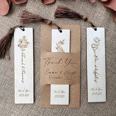 two wooden tags with flowers and tassels attached to them on a piece of brown paper