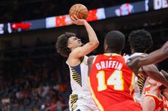 the basketball player is trying to block the ball from being blocked by two other players