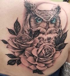 an owl and rose tattoo on the back of a woman's shoulder with blue eyes