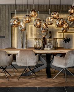 a dining room table with chairs and lights hanging from the ceiling