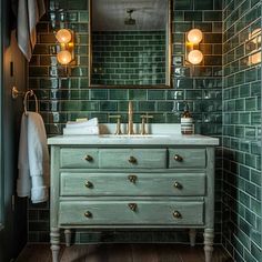 a bathroom with green tiled walls and wooden flooring, two gold faucets on the sink