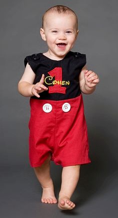 a baby is smiling and wearing red shorts