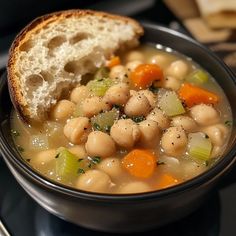 a close up of a bowl of food on a plate with bread in the background