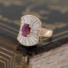 The best pop of color on the finger with this ruby ballerina ring. The ruby is a beautiful, rich deep reddish pink, and contrasts so beautifully against the white diamonds. And speaking of which, the long and narrow tapered baguettes are the most dramatic we have seen in sometime - the perfect back drop for this gorgeous ruby. 18kt yellow gold, size 5.5 & fully resizable.Ruby is estimated to be VS1 type II clarity.Diamonds are estimated to be G/H colors & VVS/VS1 clarities.Please see qua Red Ruby Ring With Baguette Diamonds, Luxury Ruby Ring With Baguette Diamonds, Red Baguette Diamond Wedding Rings, Wedding Rings With Ruby And Baguette Diamonds, Fine Jewelry Ruby Ring With Baguette Diamonds For Wedding, Wedding Ruby Ring With Baguette Diamonds, Jewelry Goals, Diamond Ballerina Ring, Gold Thumb Rings