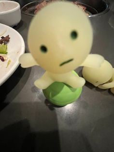 a small plastic toy sitting on top of a table next to a plate of food