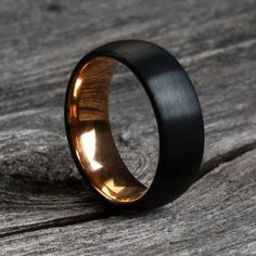 a black and gold wedding ring on top of a piece of wood