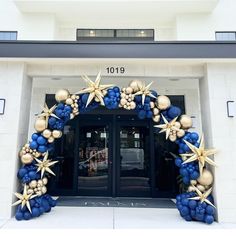 an entrance to a building decorated with blue and gold balloons, starbursts, and other decorations