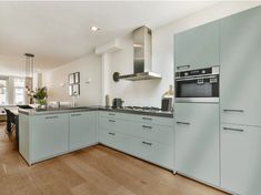 a kitchen with white cabinets and light blue counter tops, an oven and stove hood