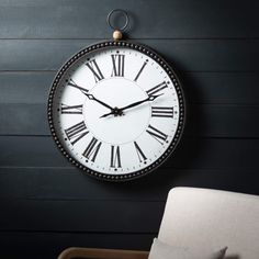 a black and white clock hanging on the wall next to a chair in a room