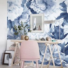 a desk with a pink chair in front of a blue flower wallpapered room