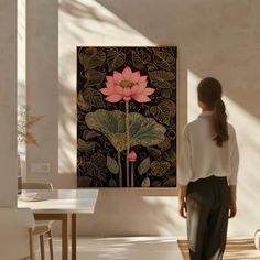 a woman standing in front of a painting with a pink flower on it's side