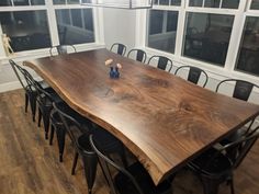 a wooden table surrounded by black chairs in a room with large windows and wood flooring