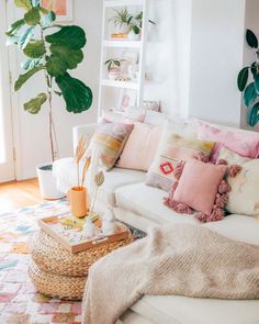 a living room filled with lots of white furniture and plants on top of the walls