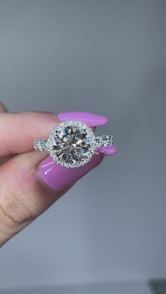 a woman's hand holding an engagement ring with two diamonds on the top and bottom