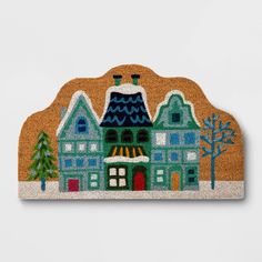 a door mat with a house on the front and trees on the back in winter