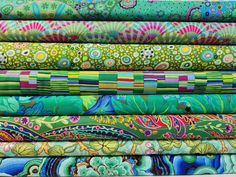 a stack of colorful fabrics with different patterns and colors on the fabric, including blue, green