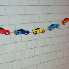 colorful cars are lined up on a line against a white brick wall in the shape of numbers