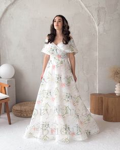 a woman in a white floral dress standing next to a chair