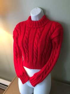 a mannequin with a red sweater on it's head and torso in front of a white wall