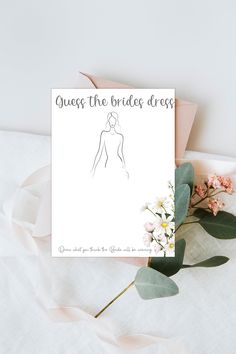 a card with the bride's dress on it next to some flowers and leaves