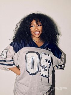 a woman wearing a football jersey with her hair in the air and smiling at the camera