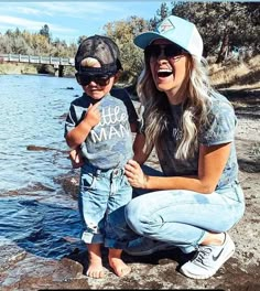 a woman and child are sitting on the rocks by the water with their mouths open