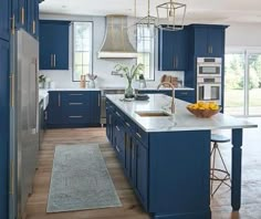 a large kitchen with blue cabinets and white counter tops, an island in the middle