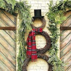 a snowman made out of wreaths and greenery with a top hat on