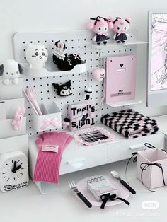 a white desk topped with lots of pink items next to a black and white wall