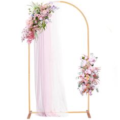 an arch decorated with pink flowers and greenery next to a white drapeed backdrop