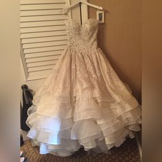 a wedding dress hanging on a hanger in front of a door with shutters