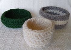 three crocheted bowls sitting on top of a white bed next to each other