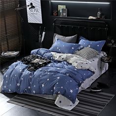 a bed with blue comforters and white stars on it in a black bedroom area