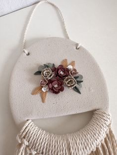 a white wall hanging with flowers and tassels attached to the back of it