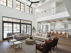 a living room filled with lots of furniture next to a tall white ceiling mounted fan