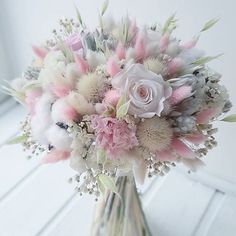 a vase filled with lots of flowers on top of a white table next to a window