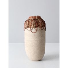 a ceramic vase with wire wrapped around it's top and bottom, sitting on a white surface