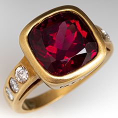 This bezel ring is centered with one (1) cushion mixed cut natural rhodolite garnet set into a bezel setting. The shoulders of the ring are each accented with three (3), flush set, round brilliant cut diamonds. The ring measures 13.5mm at the top, rises 8.7mm above the finger, tapering to 2.6mm wide and 0.9mm thick at the base of the shank. Signed TOROS. It is a size 7.25. We are not offering resizing due to the design of the ring. The ring shows some nice patina. Red Garnet Ring 1stdibs, Ruby Ring Designs Unique, Ruby Ring Designs, Rhodolite Garnet Ring, Bezel Ring, Garnet Ring, Rhodolite Garnet, Garnet Rings, Ruby Ring