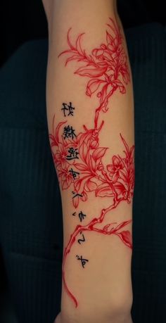 a woman's arm with chinese writing on it and flowers painted on the side