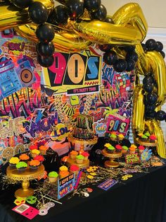 a table topped with lots of balloons and desserts next to a black table cloth