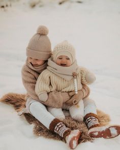 two babies are sitting in the snow together