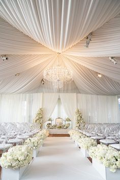 a wedding ceremony setup with white flowers and chandelier hanging from the ceiling,