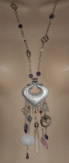 "This handcrafted bohemian, hippie, boho necklace has been created from amethyst stone beads, wire wrapped crystal points, hamsa charms, spiritial head charm beads, an OHM charm with a tiny amethyst inset stone and a carved glass lotus pendant.  The overall length from lobster clasp closure to bottom of crystal point measures 19 1/2\". The antique silver tone metal pendant along measures 2 1/4\" wide and 2 1/4\" tall." Wrapped Crystal Point, Wire Wrapped Crystal, Lotus Pendant, Hamsa Charm, Chevron Necklace, Crystal Amethyst, Wrapped Crystal, Surfer Style, Witch Jewelry