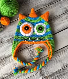 a crocheted hat with an orange, green and blue owl on the front