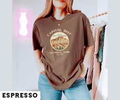 🏜️ Celebrate the rugged beauty of Capitol Reef with this Vintage National Park Shirt, featuring a stunning canyon graphic and the establishment year 1971. Perfect for outdoor enthusiasts, this retro tee captures the essence of Capitol Reef's breathtaking landscapes. Ideal for hiking, camping, or simply showing off your love for the great outdoors, this shirt makes a fantastic gift for friends and family who appreciate national parks and vintage style. 🏞️This design style is available for many Casual Brown Tops For Outdoor Activities, Brown Relaxed Fit Top For Outdoor, Retro Crew Neck Tops For Outdoor Activities, Vintage Pre-shrunk Tops For Outdoor Activities, Pre-shrunk Vintage Tops For Outdoor Activities, Vintage Letter Print Tops For Outdoor Activities, Vintage Tops With Letter Print For Outdoor Activities, National Park Gifts, National Park Shirt